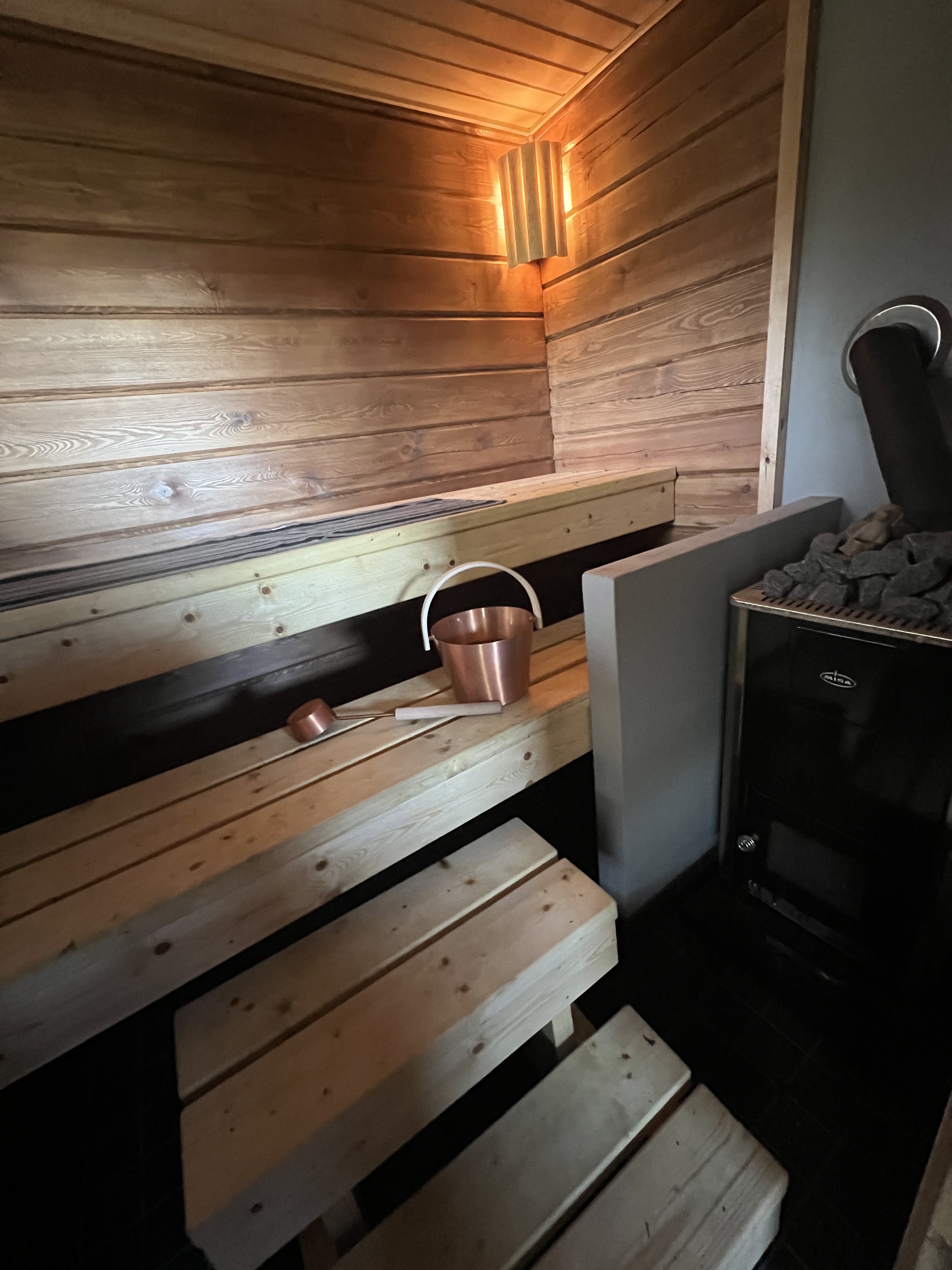 Puipaneelinen sauna kuparisella ämpärillä ja kiukaalla